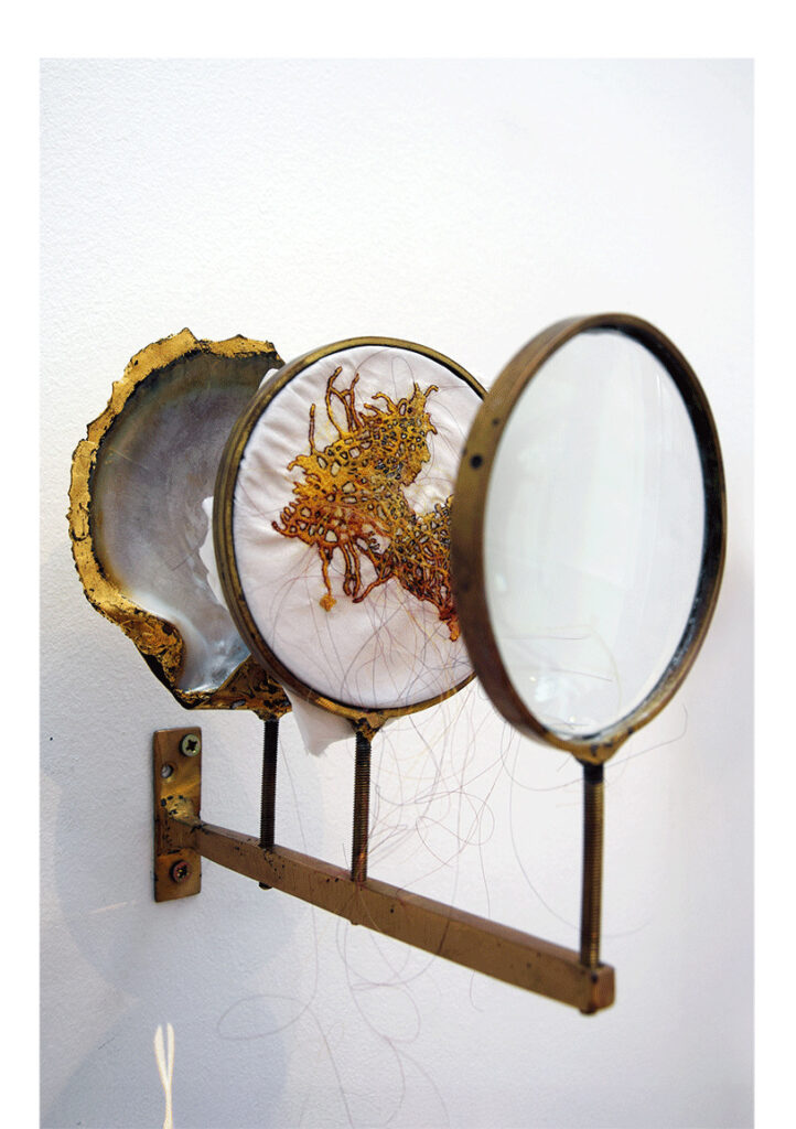 Laura Sánchez Filomeno | Micro organisme IV (Nautilus) | Broderie en cheveux naturels et colorées sur soie, coquillage, loupe, feuille d'or et bronze | 15 x 13 x 23 cm | 2022
